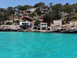 Cala de Mallorca mit türkisfarbenem Wasser und auf dem Felsen gebauten Häusern, wo Palma Finance zu Liquidität bei Immobilieninvestitionen berät