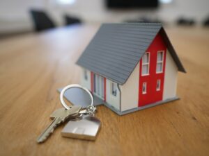Miniatur-Haus in Rot mit Schlüsseln auf einem Tisch – die Lösung von Palma Finance für den Kauf einer Immobilie vor dem Verkauf Ihres Hauses auf Mallorca